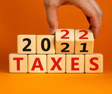 2022 taxes new year symbol. Businessman turns wooden cubes and changes words 'Taxes 2021' to 'Taxes 2022'. Beautiful orange background, copy space. Business, 2022 taxes new year concept.