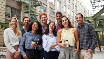 Friendly coworkers laugh to camera outside their workplace