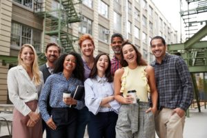 Friendly coworkers laugh to camera outside their workplace